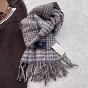 Detailed close-up of wool blend plaid scarf with blue fringe and woven brand label