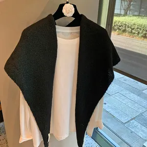 Detail of a black knitted shawl wrap with a triangular design over a white shirt