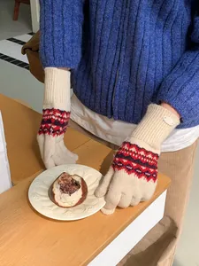 Nahaufnahme von Fair-Isle-Strickhandschuhen in Beige mit rot-blauen Mustern