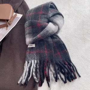 Detail shot of the thick wool blend plaid scarf with red patterns and soft fringes