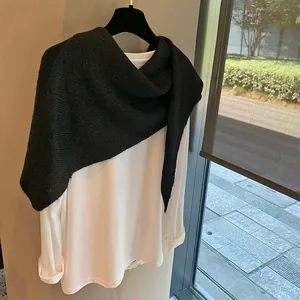 Close-up of black knitted shawl texture over a casual white long sleeve cotton top