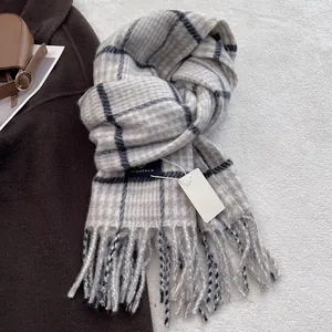 Detailed view of grey and blue plaid wool scarf featuring soft fringe and brand label