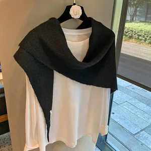 Detailed texture of black knit shawl wrap draped elegantly over a white long-sleeve shirt