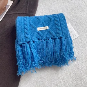 Detailed view of blue cable knit 100% wool scarf featuring thick tassels and premium texture