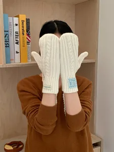 Detail of cream cable knit gloves with decorative fabric labels and woven texture