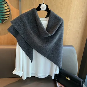 Detail of soft 100% wool knit triangle scarf in dark grey draped on white base layer