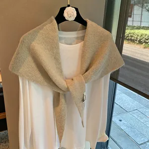 Detail of light coffee knitted shawl with fluffy texture and branded woven label