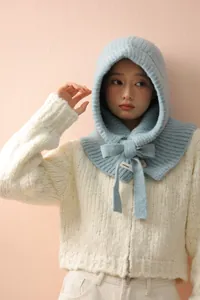 Détail d'une cagoule en tricot bleu clair avec nœud ruban et étiquette tissée