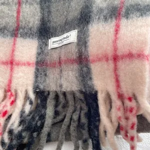 Detail shot of the thick plaid wool blend scarf with fringe edges and brand label