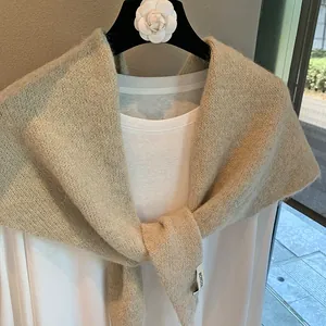 Close-up of light beige knitted shawl showing soft texture and BONOGE brand side label