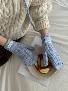Close-up of light blue cable knit gloves with warm wool texture and woven tag detail
