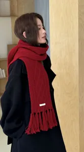 Detail of red cable knit wool scarf with long tassels paired with a black wool coat