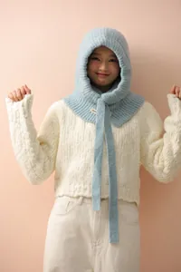 Détail d'une cagoule tricotée bleu clair montrant la texture côtelée et le mélange de laine