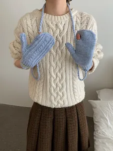 Detail of light blue cable knit texture and neck strap on cute winter gloves