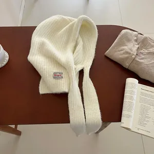 Detail of soft cream knitted balaclava showing ribbed texture and a woven logo label