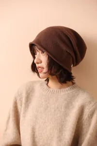 Dettaglio del berretto in maglia marrone scuro con bordo arrotolato e maglione