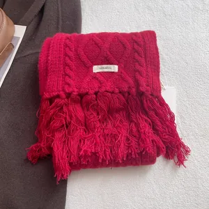 Detail view of red 100% wool scarf featuring classic cable knit pattern and soft fringe edges