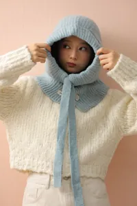 Détail de cagoule en tricot bleu clair avec texture en laine épaisse et bouton