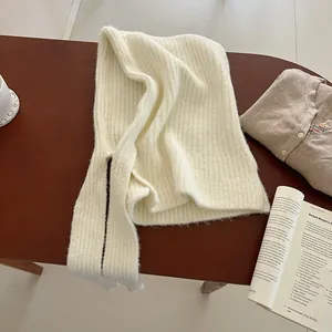 Detail of soft cream chunky ribbed knit balaclava texture on warm wooden desk