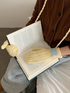 Detail of cable knit mittens in cream beige with a convenient neck strap design