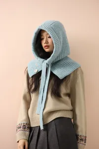 Détail de la cagoule tricotée bleu clair avec texture côtelée, cordon et bouton blanc