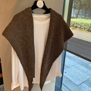 Close-up of fluffy dark brown knit shawl with mohair texture and branded woven label