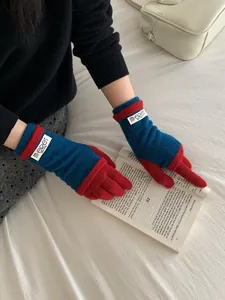 Detailed view of heavy knit contrast gloves in navy and red with brand cuff tag