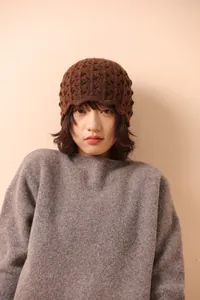 Detailed knit texture of dark brown 100% wool crochet beanie with hollow edge design
