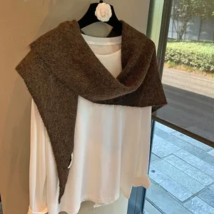 Close-up of soft dark brown knit shawl with plush texture over a white T-shirt
