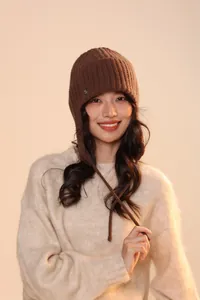 Dettaglio cappello in maglia a coste marrone scuro con paraorecchie e lacci spessi