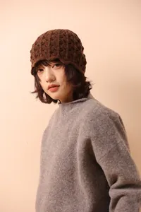Close-up of brown wool blend knit bucket hat featuring intricate hollow crochet design details