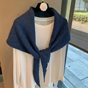 Detailed close-up of dark blue knit shawl texture with elegant knot on white shirt