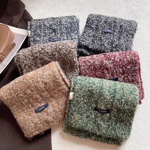 Sciarpe in misto lana boucle in sei colori con etichetta tessuta su sfondo bianco