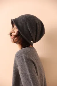 Dettaglio del berretto in maglia grigio scuro con trama e etichetta del materiale al 100%