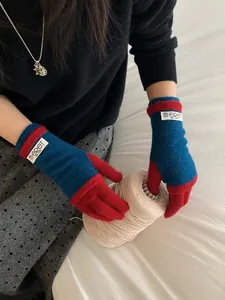 Detail of blue and red knit touchscreen gloves with brand tag in a warm lifestyle setting