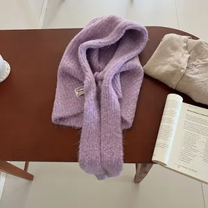 Detailed close-up of a purple knitted balaclava with brand tag on a rustic wooden desk