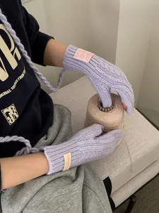 Close-up of lavender cable-knit gloves with neck strap and decorative fabric label