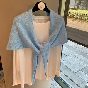 Detail of sky blue knitted mohair shawl with logo label and soft fuzzy texture