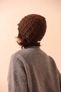 Detailed macro shot of the 100% wool label on the dark brown chunky knit beanie hat