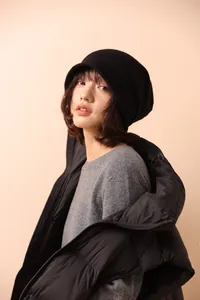 Dettaglio della texture del berretto in maglia nera con un outfit invernale