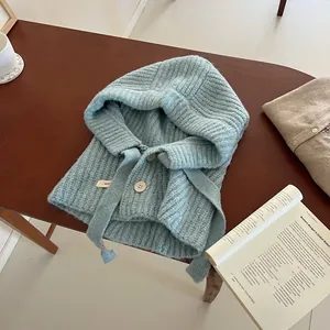 Détail d'une cagoule bleu clair en grosse maille avec boutons en bois et cordon