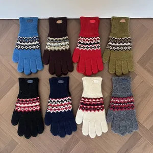 Flachbild von Fair-Isle-Strickhandschuhen in acht Farben mit geometrischem Muster auf Holz