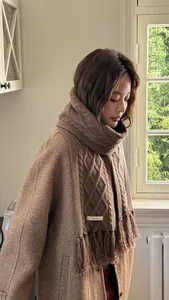 Detail showing 100% pure wool label and twisted knit texture of the brown tassel scarf