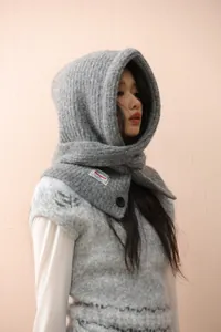 Detail of grey knitted balaclava hood with wavy texture and button ornament