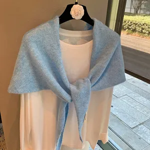 Detail of light blue fuzzy knitted shawl with knot design and soft texture for layering