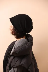 Dettaglio del berretto in maglia nera con bordi arrotolati su una modella in inverno