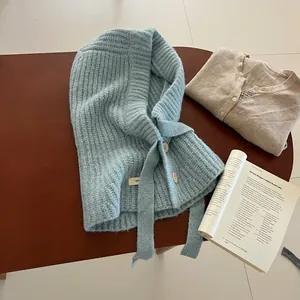 Texture détaillée d'une cagoule en tricot bleu clair avec boutons blancs sur bois rustique