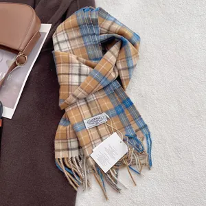 Close-up of a plaid wool scarf with fringes, brand label and stylish autumn accessories