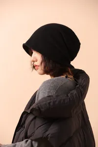 Texture dettagliata del berretto in maglia nera con bordo arrotolato indossato dal modello