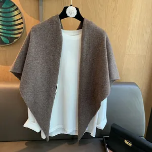 Close-up of brown 100% wool knit shawl with brand wash label and camellia hanger